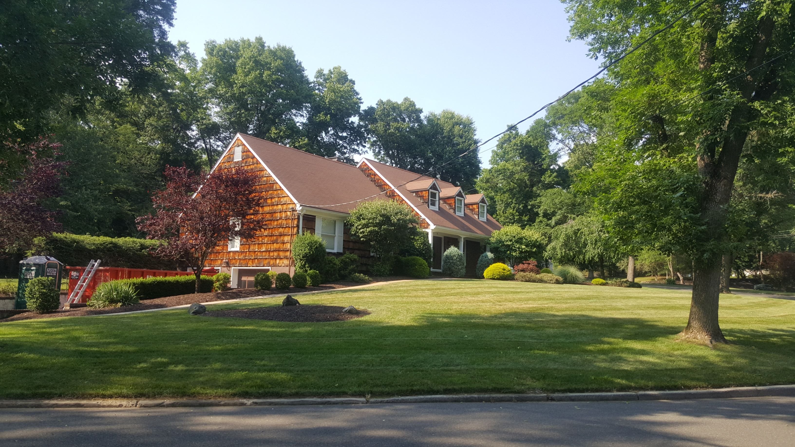 The dated exterior of the home with brown roof and weathered shake siding